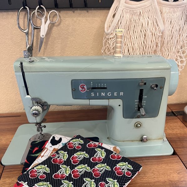Singer sewing maching with scissors, thread, and quilt patches sitting ready to use.