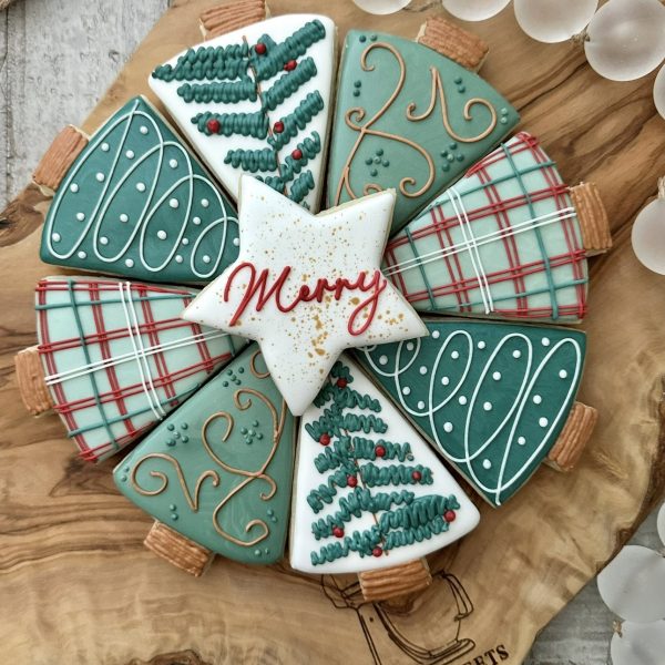 Collection of christmas tree cookies with royal icing details. One star sugar cookie on the top states "Merry" in red frosting.